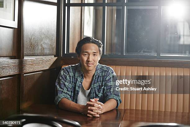 young man sitting at table, wood tones - australian culture stock photos et images de collection