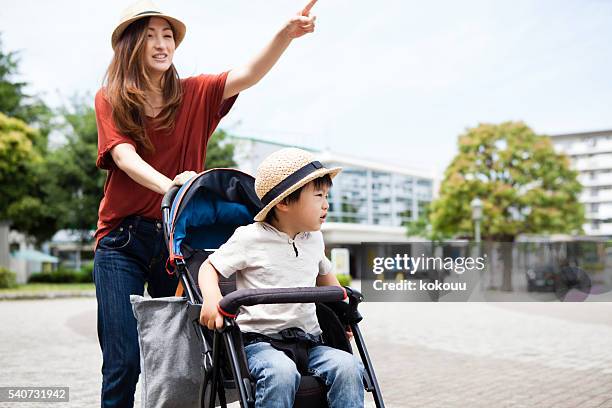 mother pushing a stroller in the park - trip hazard stock pictures, royalty-free photos & images
