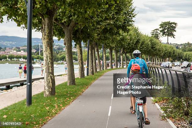 people bike riding along lake - lac d'annecy photos et images de collection