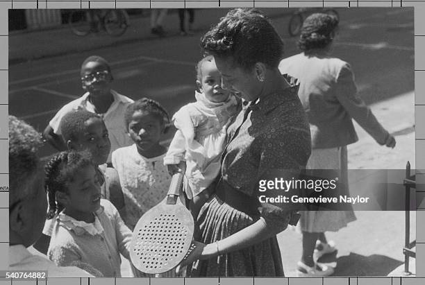 Children gather around tennis champion Althea Gibson on a Harlem street.
