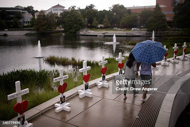 Couple walks past a memorial with wooden crosses for each of the 49 victims of the Pulse Nightclub next to the Orlando Regional Medical Center, June...