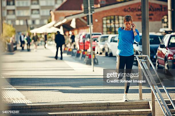 young jogger stretching while on the phone - uppsala stock pictures, royalty-free photos & images