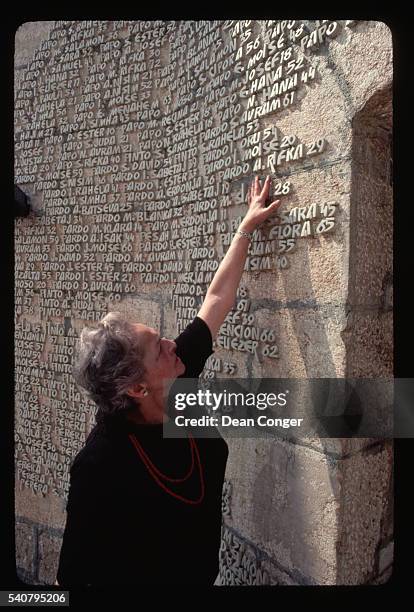 Antonia Radmil Slosberg, a Jew who survived by changing her name to the Serbian name Antonia Radmila Babic, touches a name at a memorial to Jews...