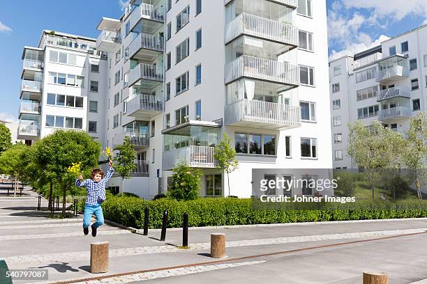 boy jumping over concrete pole - modern apartment balcony stockfoto's en -beelden