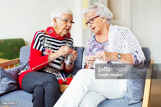senior women discussing while knitting at nursing home - knit stockfoto's en -beelden