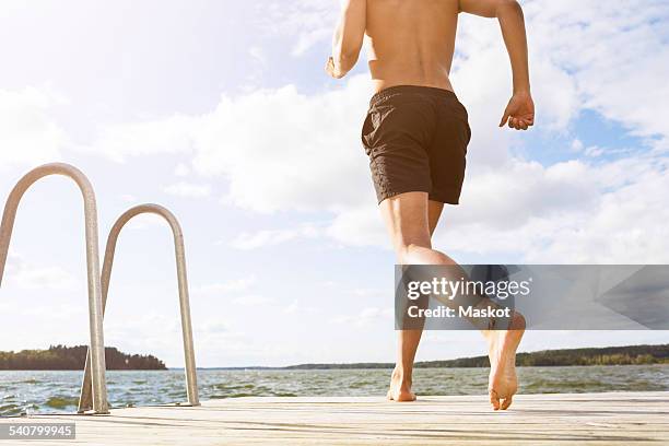 low section of man running on boardwalk at lake - swimming trunks stock pictures, royalty-free photos & images