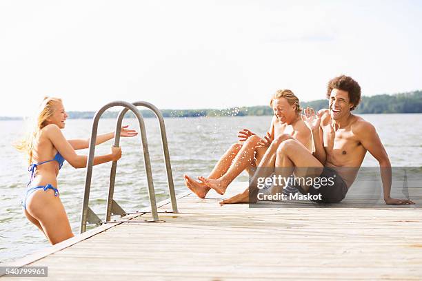 playful friends on boardwalk at lake - stockholm beach stock pictures, royalty-free photos & images