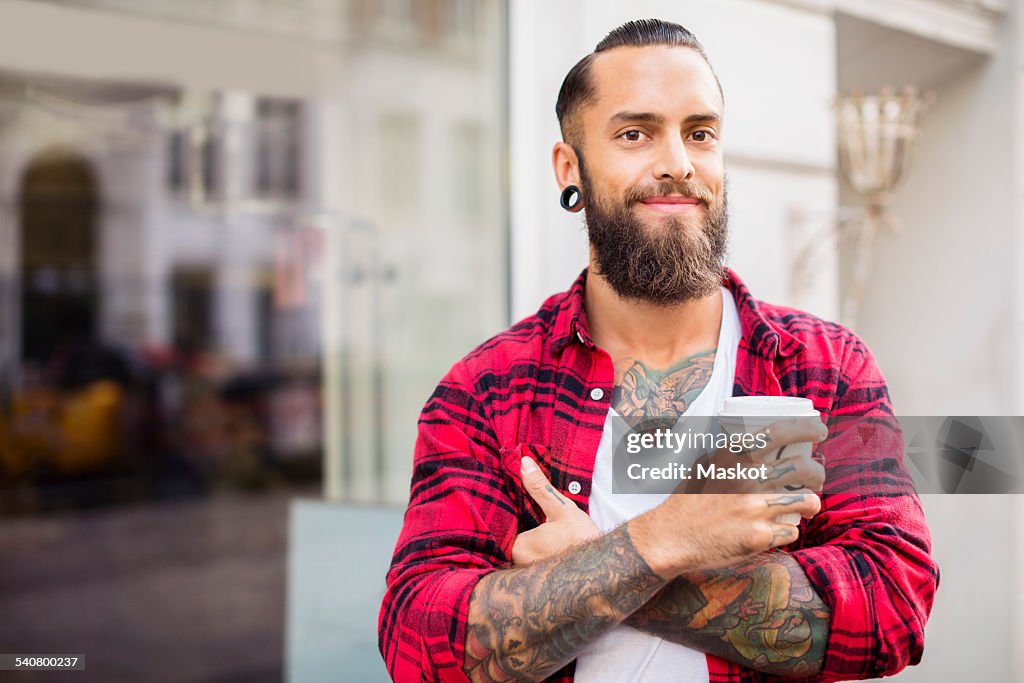Portrait of smiling owner with coffee outside candy store