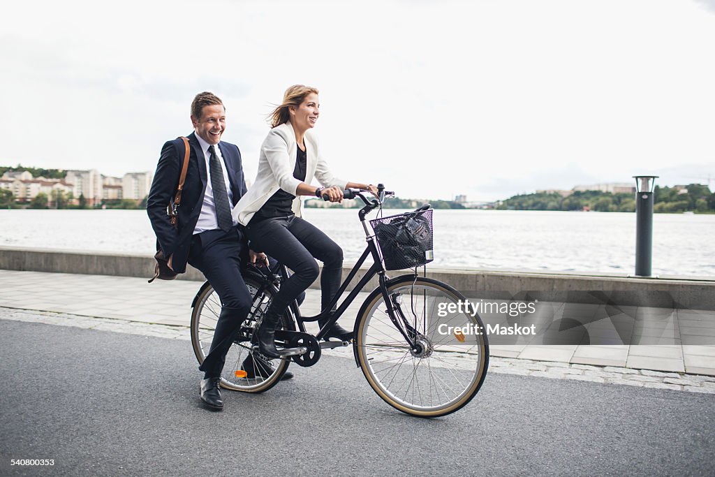 Happy business people riding on bicycle in city street