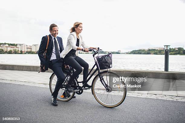 happy business people riding on bicycle in city street - permanent representative stock pictures, royalty-free photos & images