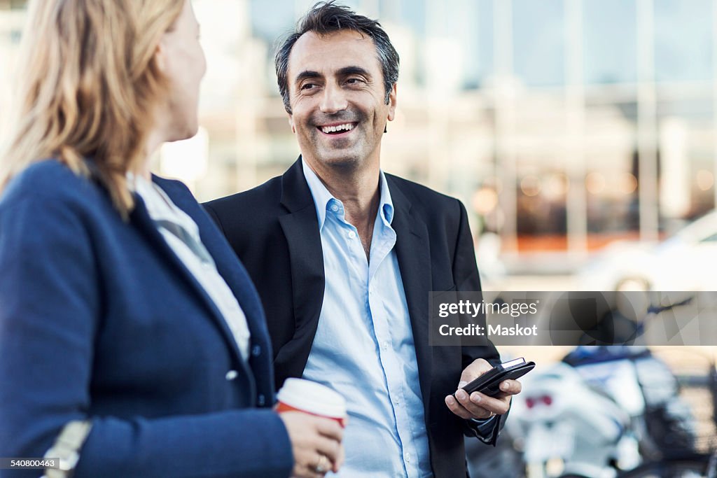 Happy businessman talking to female colleague outdoors