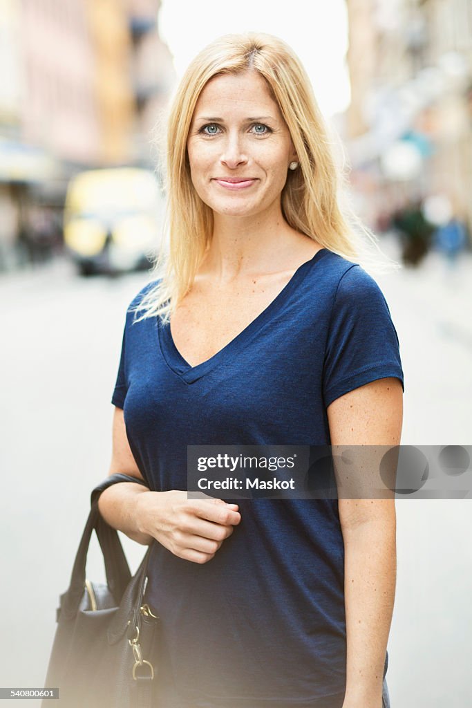 Portrait of smiling mid adult woman standing on street in city