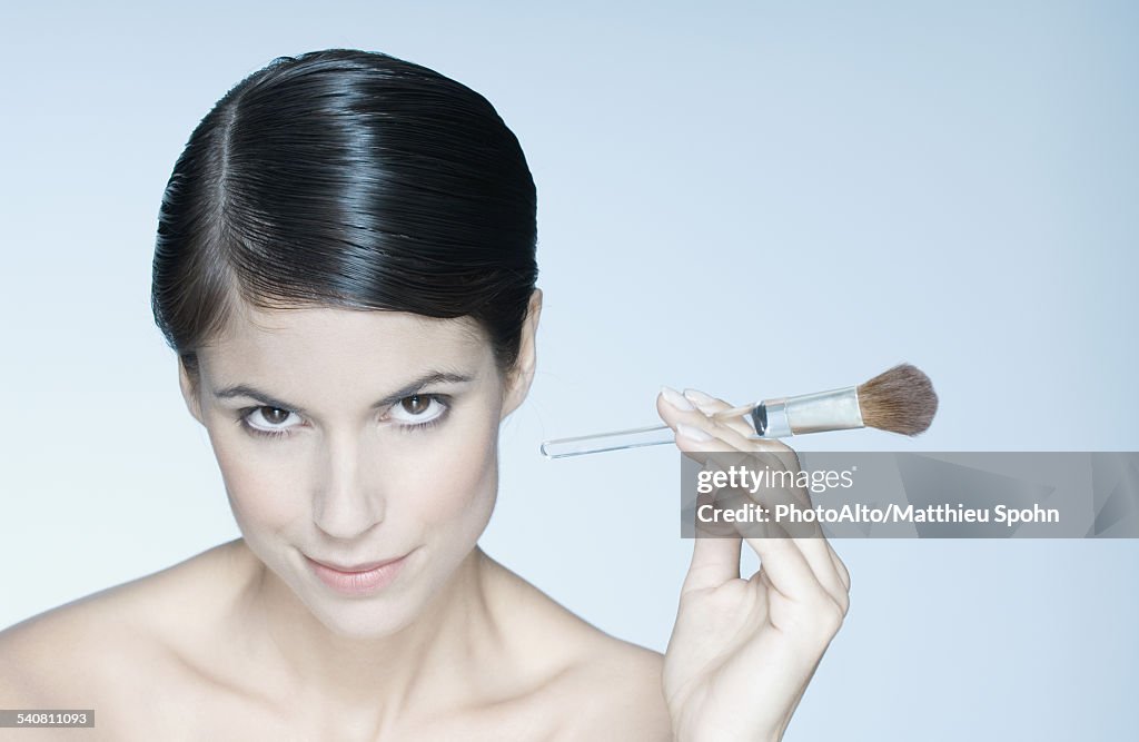 Woman holding make-up brush, portrait