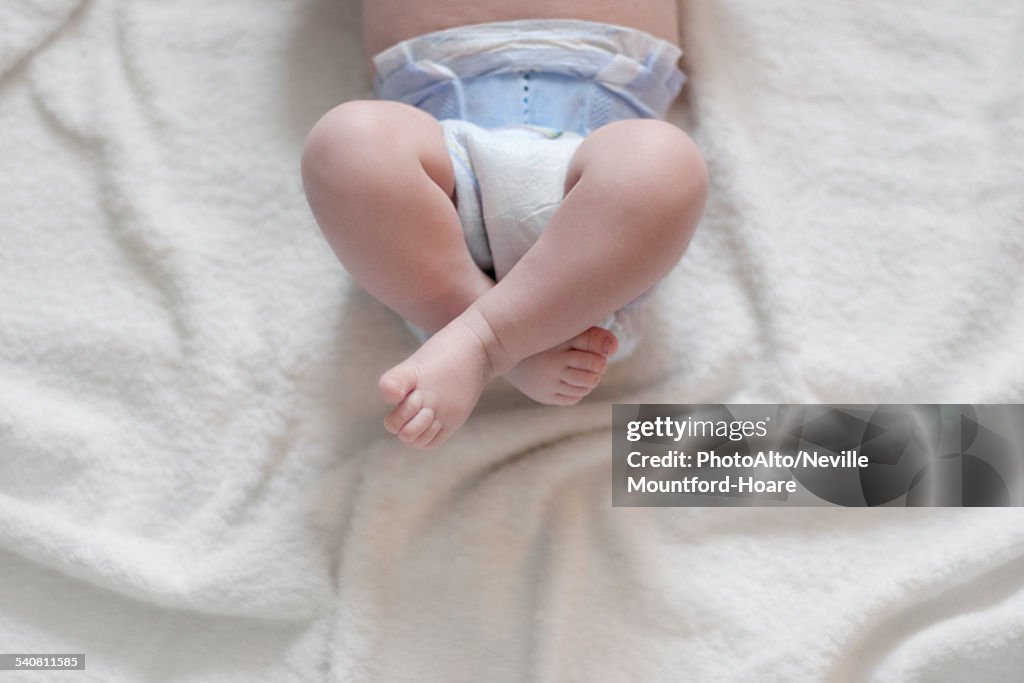 Baby in diaper lying on back with legs up, cropped