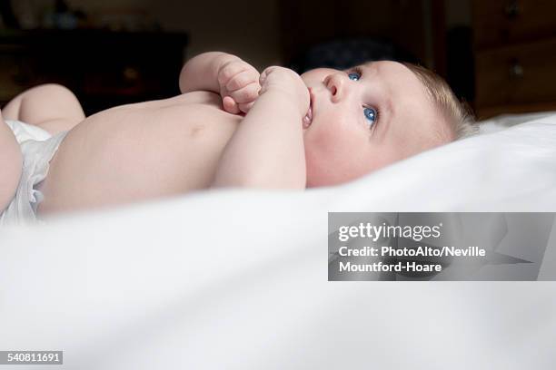 baby lying on back with finger in mouth - finger in mouth stock pictures, royalty-free photos & images