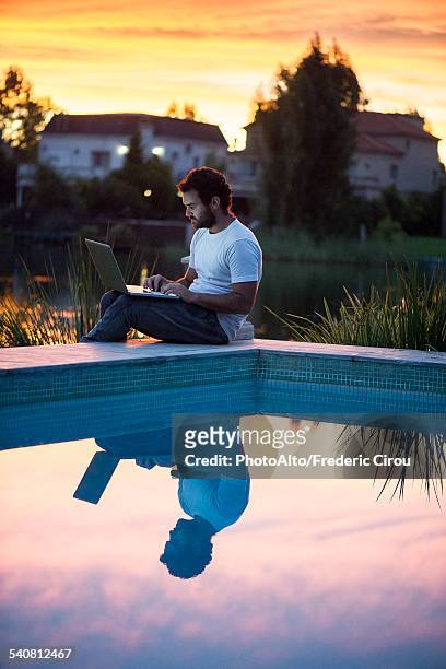 man using laptop computer next to swimming pool as sun sets - buenos aires sunset stock pictures, royalty-free photos & images