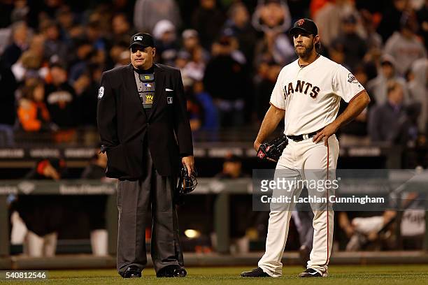 Home plate umpire Andy Fletcher waits with Madison Bumgarner of the San Francisco Giants while the Milwaukee Brewers coaches decide not to challenge...