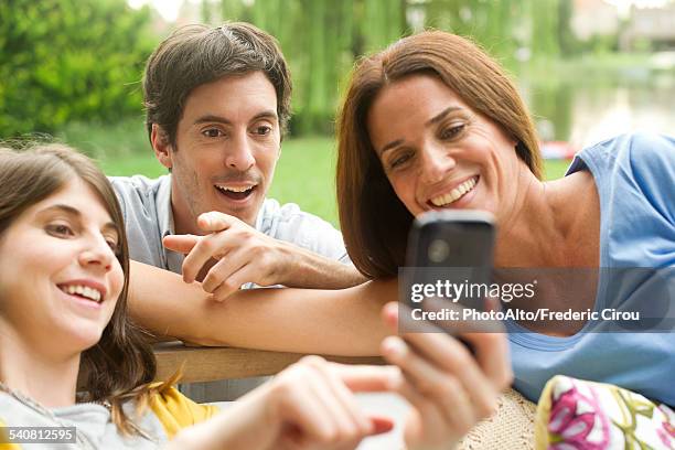 young woman sharing photos on smartphone with friends - famiglia multimediale foto e immagini stock