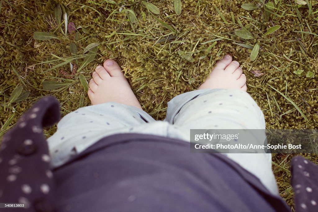 Baby walking on grass, cropped personal perspective