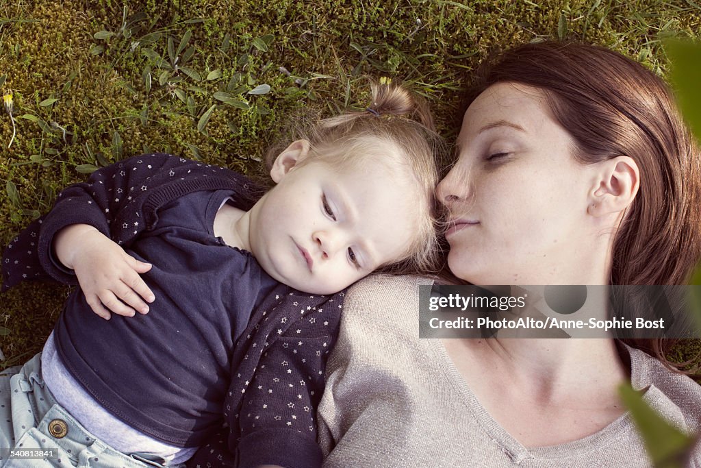 Mother and baby girl napping on grass