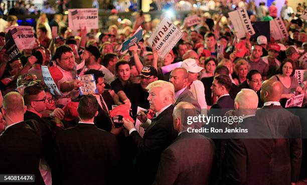 Flanked by members of the Secret Service, Republican presidential candidate Donald Trump, center, signs for supporters as stage lights paint the...