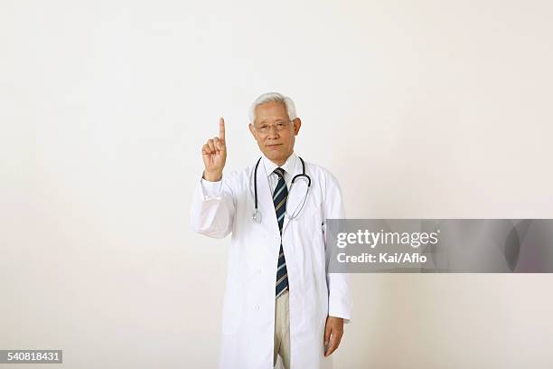 senior adult japanese doctor against white wall - index finger stock pictures, royalty-free photos & images