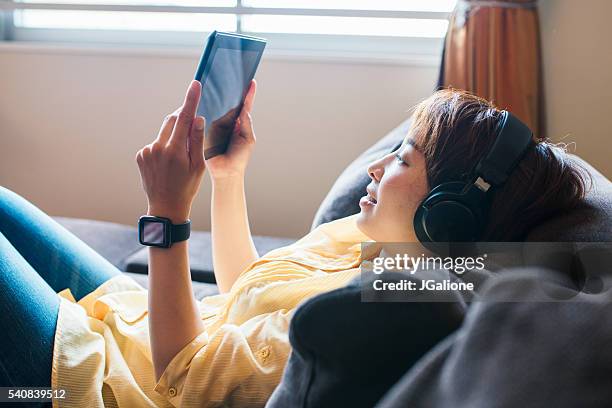 mujer joven usando tableta digital - headphones asian fotografías e imágenes de stock