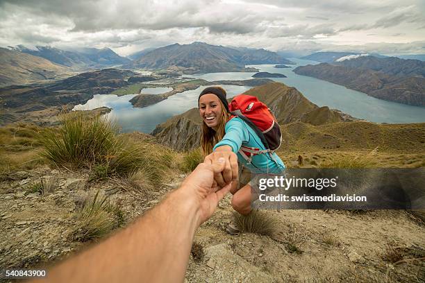 woman hiking pulls out hand to get assistance from teammate - reaching higher stock pictures, royalty-free photos & images