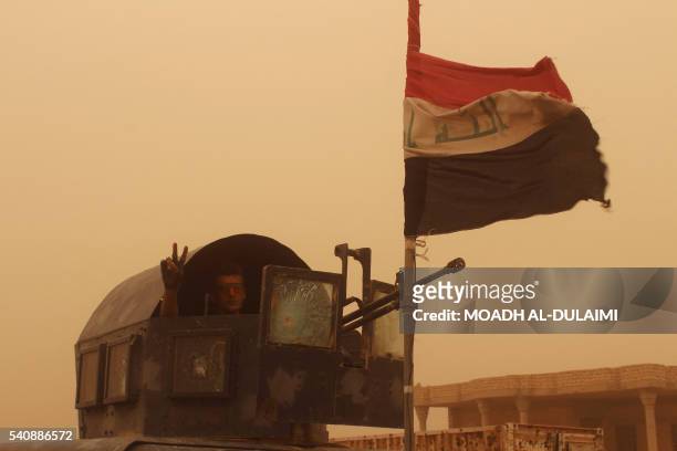 Member of the the Iraqi government forces flashes the "V" for victory sign on June 16, 2016 after recapturing the town of Zankura, northwest of...