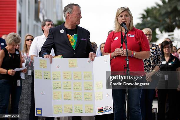 Surrounded by members of federal, state and local agencies, Orlando Mayor Buddy Dyer looks on as Red Cross volunteer Amy Decker speaks at a press...