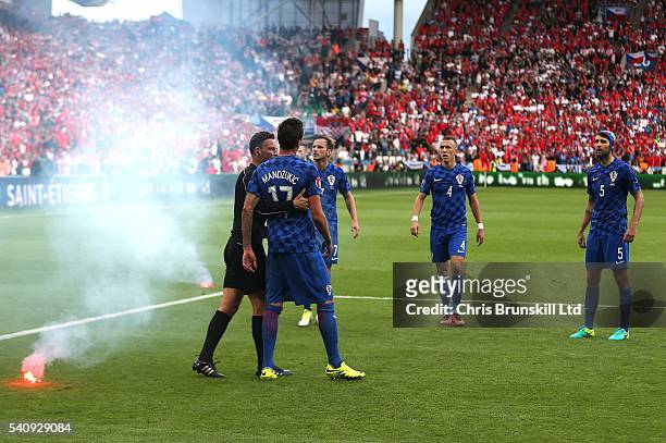Referee Mark Clattenburg ushers Mario Mandzukic of Croatia away from a flare that was thrown on the pitch during the UEFA Euro 2016 Group D match...