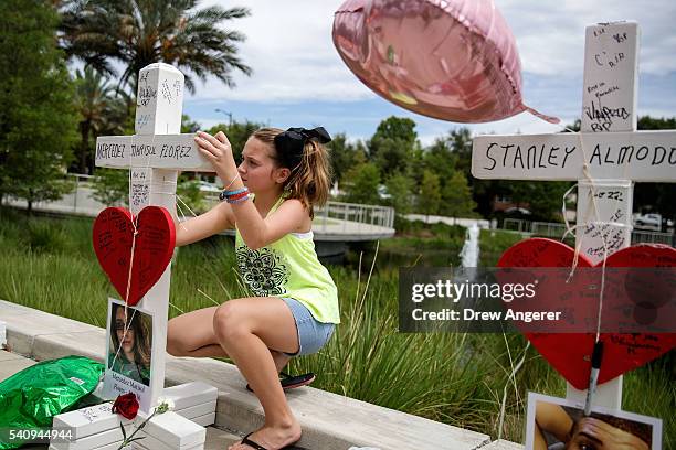 Young girl writes a note on each cross at a memorial with wooden crosses for the 49 victims of the Pulse Nightclub shooting, next to the Orlando...