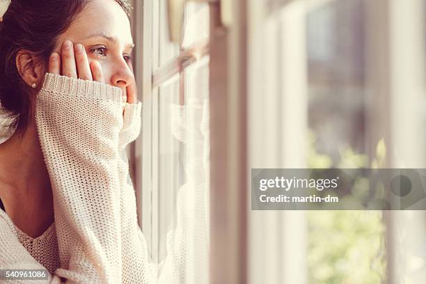 niña mirando a través de la ventana - nervioso fotografías e imágenes de stock
