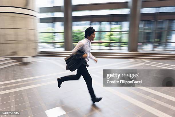 japanese businessman running to arrive on time - businessman running stock pictures, royalty-free photos & images