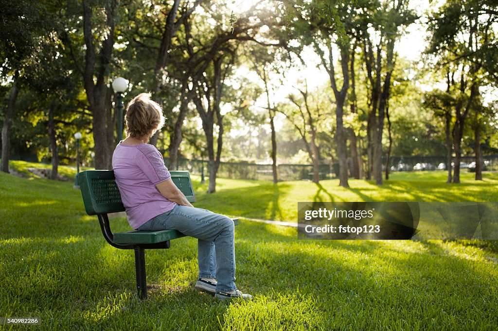 Rear view of mature woman sitting on park bench.  Summer.