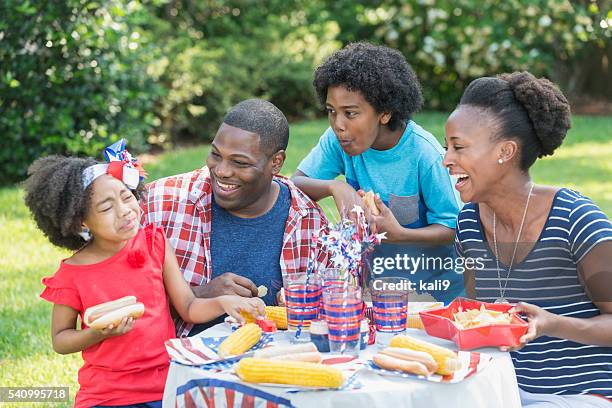 african american mixed race family at july 4th picnic - asian eating hotdog stockfoto's en -beelden