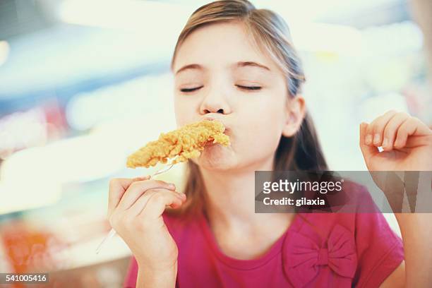 little girl eating fried chicken. - breaded stock pictures, royalty-free photos & images
