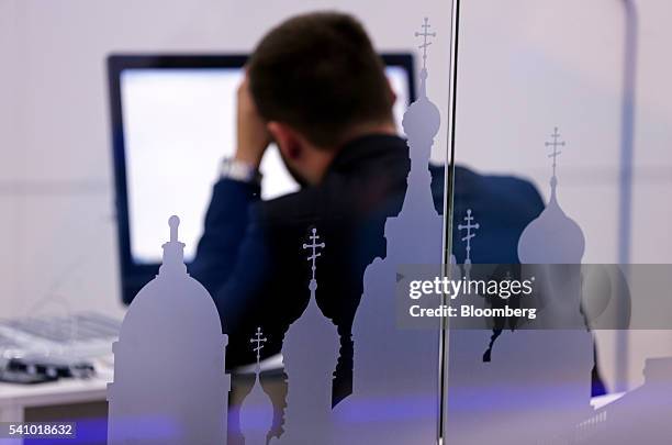 An attendee works at a computer terminal behind a glass graphic of Russian orthodox church domes on the closing day of the St. Petersburg...