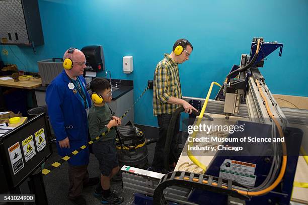 With his teacher, a student watches another man as he uses a 'ShopBot' for computer-aided design and fabrication during a summer school course at the...