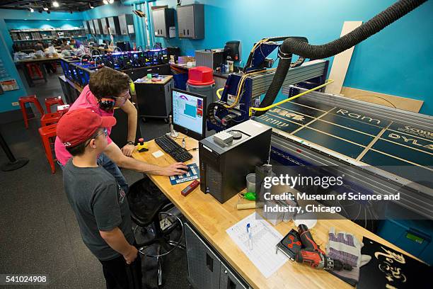 Assisted by a teacher, a student uses a 'ShopBot' for computer-aided design and fabrication during a summer school course at the Museum of Science...