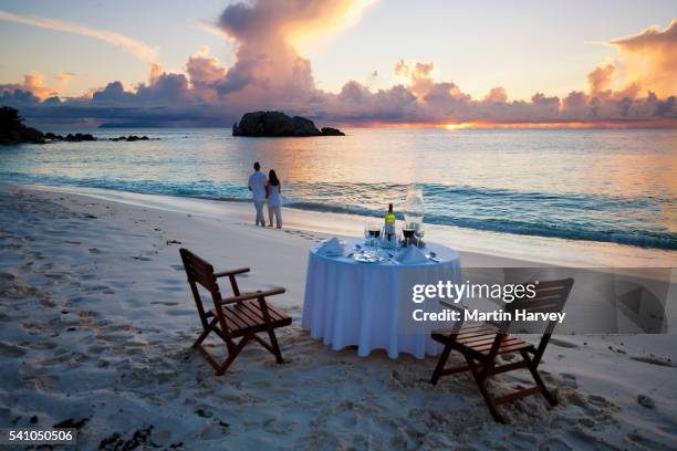 romantic couple walking at sunset on beach with dinner table in foreground.cousine island.seychelles - escape stock pictures, royalty-free photos & images