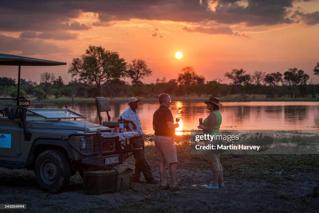 Tourists enjoying a sundowner on the banks of the Khwai river.Okavango Delta.Machaba camp.Botswana