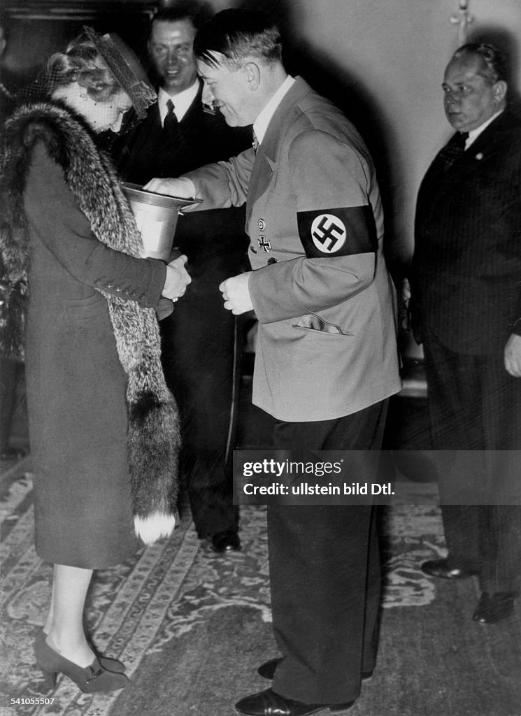 Adolf Hitler donates money to Magda Goebbels. 'Tag der nationalen Solidaritaet' (Day of national solidarity). In the middle: Julius Schaub (Hitler's adjutant) and the photographer Heinrich Hoffmann.