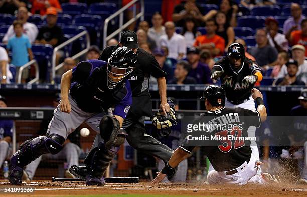 Derek Dietrich of the Miami Marlins slides past the tag of Nick Hundley of the Colorado Rockies during a game at Marlins Park on June 18, 2016 in...