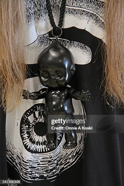 Hitomi is wearing an M:E gothic shirt, an oversized black Kewpie Doll necklace, Paris Miki eyeglasses, a CA4LA hat, a clear pvc wrist cuff, a...