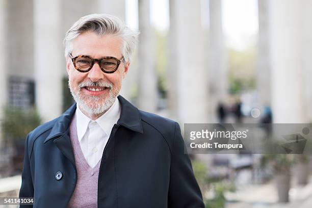 parissien man smiling at camera on paris streets - 50 59 years stock pictures, royalty-free photos & images