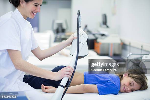 child in a physiotherapy with laser lamp treatment - infrared lamp stockfoto's en -beelden