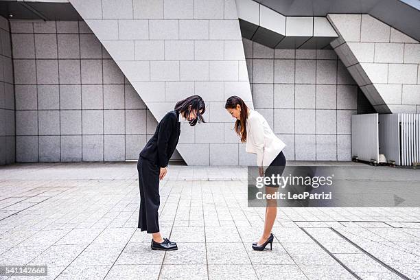 femmes d'affaires japonais dans le centre-ville de tokyo - saluer en s'inclinant photos et images de collection