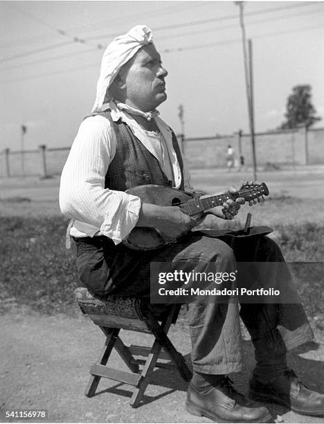 Man playing mandolin in the street. Milan, 1950s