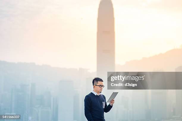 smart man using digital tablet in urban city - central district hong kong stock pictures, royalty-free photos & images